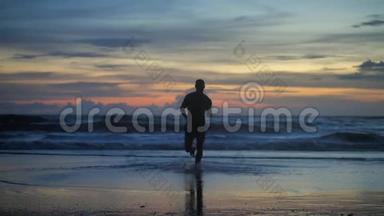 黄昏时分，在海浪的背景下，英俊的肌肉男在夕阳下奔跑的剪影